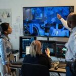 Three professionals analyzing security footage on multiple screens