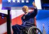 A man in a wheelchair giving a thumbs up during a political event