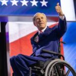 A man in a wheelchair giving a thumbs up during a political event