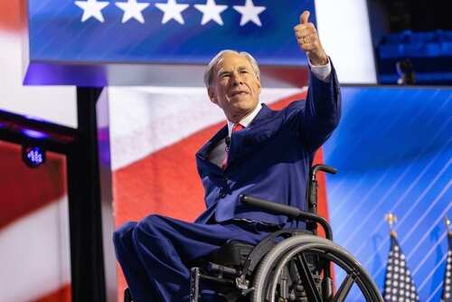 shutterstock_2664659405.jpg A man in a wheelchair giving a thumbs up during a political event