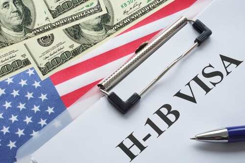 H-1B visa document on a table with US flag and dollar bills