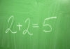 Chalkboard with the incorrect equation 2+2=5 written in white chalk