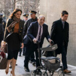 Individuals walking outside a courthouse with police presence