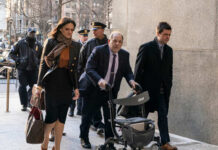 Individuals walking outside a courthouse with police presence