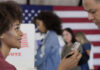 A woman showing her ID to a man at a voting station