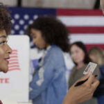 A woman showing her ID to a man at a voting station