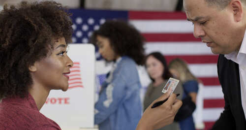 A woman showing her ID to a man at a voting station