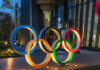 Illuminated Olympic rings displayed outside a modern building at night
