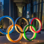Illuminated Olympic rings displayed outside a modern building at night