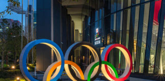 Illuminated Olympic rings displayed outside a modern building at night
