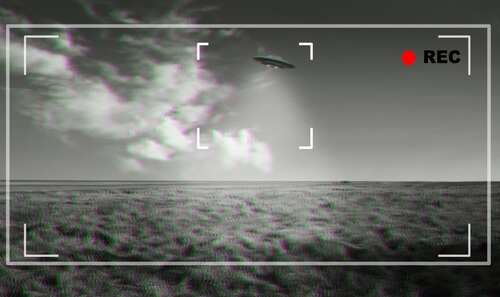 A UFO hovering above a field with a cloudy sky in the background