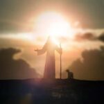 Silhouette of a figure with a staff and a dog against a sunset