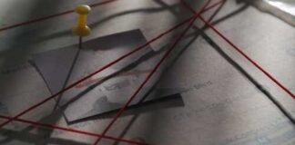 A corkboard with a photo pinned and red strings connecting various points