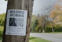 Missing person poster on a telephone pole with a woman's photo