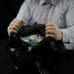 Person opening a black bag filled with cash