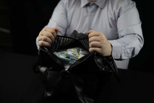 Person opening a black bag filled with cash