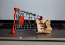 A miniature shopping cart next to a crumpled paper bag with a shopping cart icon