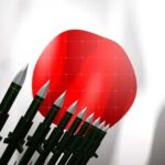 A row of military missiles in front of the Japanese flag