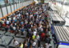 A large crowd of travelers waiting in line at an airport terminal
