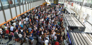 A large crowd of travelers waiting in line at an airport terminal