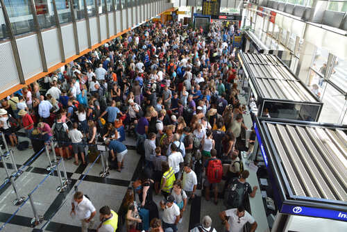 A large crowd of travelers waiting in line at an airport terminal