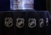 Close-up of the Stanley Cup displayed on a black tablecloth with NHL logos