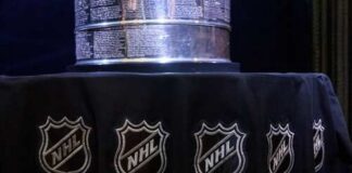 Close-up of the Stanley Cup displayed on a black tablecloth with NHL logos