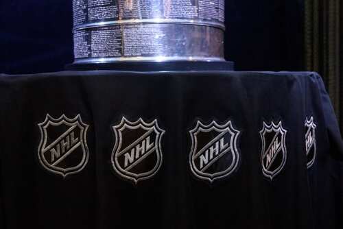 Close-up of the Stanley Cup displayed on a black tablecloth with NHL logos