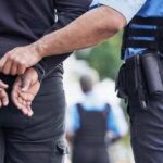 Police officer handcuffing a suspect in an outdoor setting