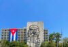 Mural of Che Guevara on a building with a Cuban flag in the foreground