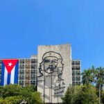 Mural of Che Guevara on a building with a Cuban flag in the foreground