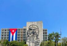 Mural of Che Guevara on a building with a Cuban flag in the foreground
