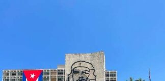 Mural of Che Guevara on a building with a Cuban flag in the foreground