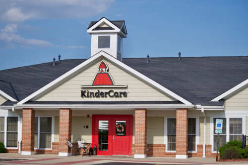 Exterior view of a KinderCare childcare center with a red door
