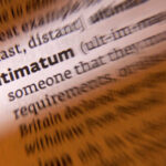 Close-up of a dictionary page highlighting the word 'ultimatum'