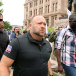 A group of men walking through a crowd at a protest