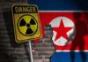North Korea Nuclear Warning Turns DARK A danger sign with a radiation symbol in front of a North Korean flag