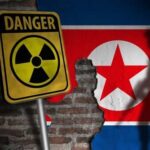 North Korea Nuclear Warning Turns DARK A danger sign with a radiation symbol in front of a North Korean flag