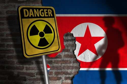 A danger sign with a radiation symbol in front of a North Korean flag