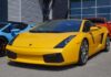 A bright yellow Lamborghini sports car parked in front of a modern building