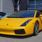 A bright yellow Lamborghini sports car parked in front of a modern building