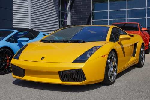 A bright yellow Lamborghini sports car parked in front of a modern building