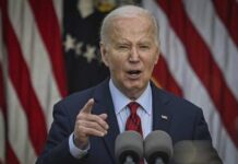 Bidens RACIAL GAFFE Caught on Camera A man in a suit delivering a speech in front of American flags