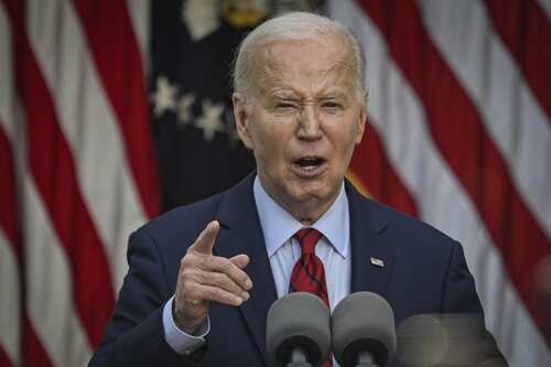 A man in a suit delivering a speech in front of American flags