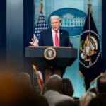 A speaker at a podium during a press conference at the White House