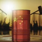 An oil barrel featuring the Chinese flag against a sunset backdrop with oil rigs
