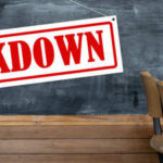 A sign reading 'LOCKDOWN' hanging in a classroom with empty chairs