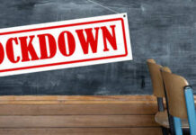 A sign reading 'LOCKDOWN' hanging in a classroom with empty chairs