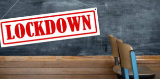 A sign reading 'LOCKDOWN' hanging in a classroom with empty chairs