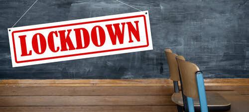 A sign reading 'LOCKDOWN' hanging in a classroom with empty chairs